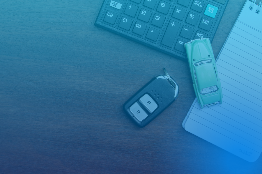 Chave de carro e miniatura de carro, com calculadora e bloco de notas, simbolizando crédito automóvel.