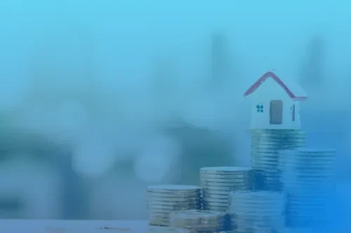 Casa em miniatura colocada sobre moedas com fundo azul.
