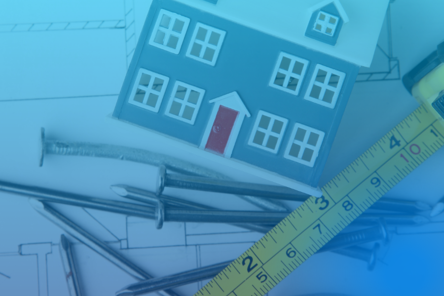 Miniatura de casa com fita métrica e pregos, simbolizando o projeto de pequenas obras ou remodelações